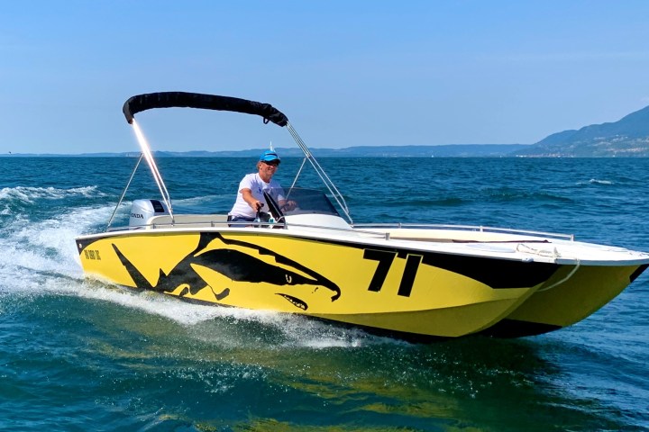 a man riding on the back of a boat in the water